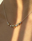 Necklace with gold and silver beads on a person wearing a white top.