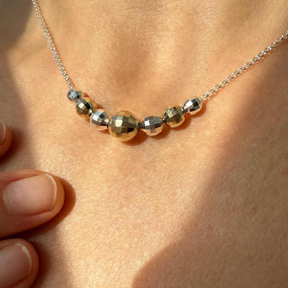 Necklace with gold and silver beads on a person's neck