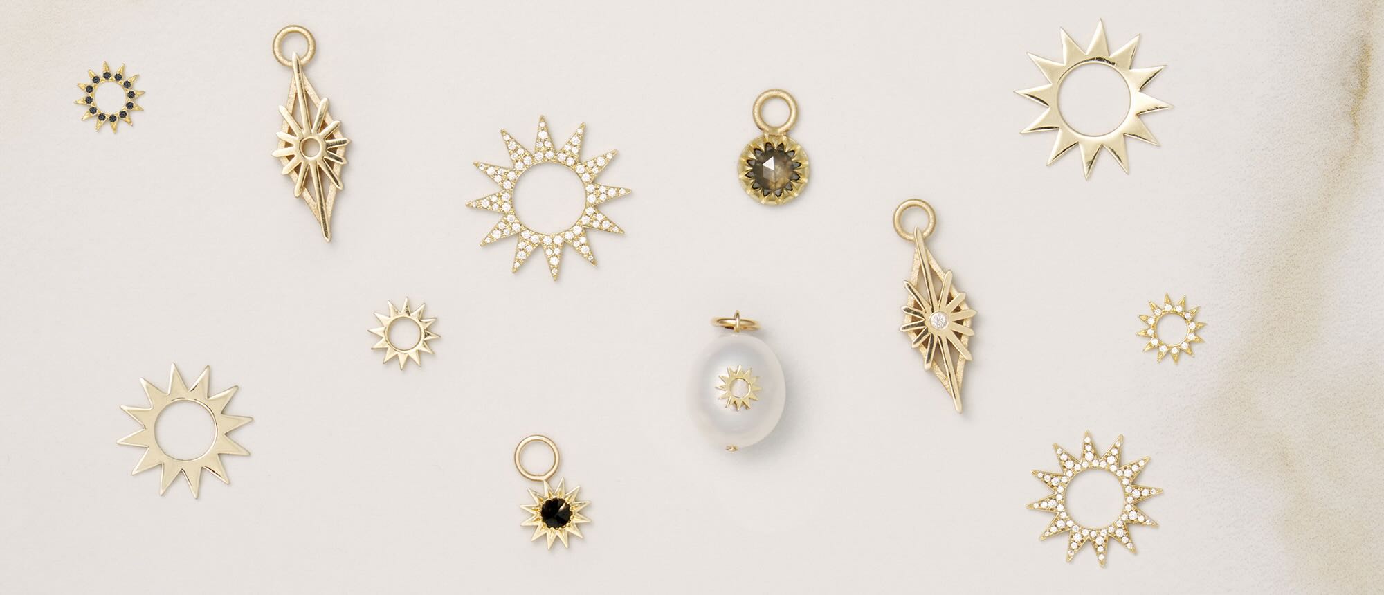 Various EMBLM Fine Jewelry earring charms on a neutral background 