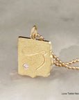 Gold pendant necklace with a diamond on a neutral background